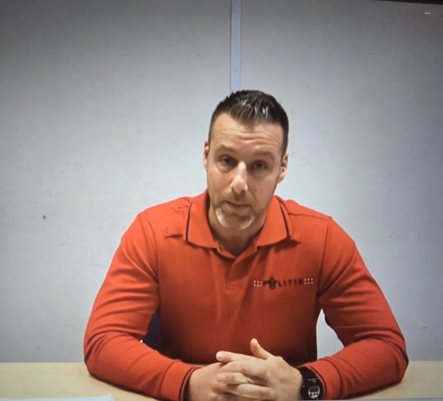 Maikel Menkhorst in een rode politiepolo aan tafel